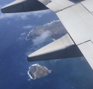 looking out of an airplane window seeing the wing and blue sky and white clouds