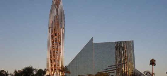 Tall cathedral spire standing alone next to a glass building that looks almost corporate.
