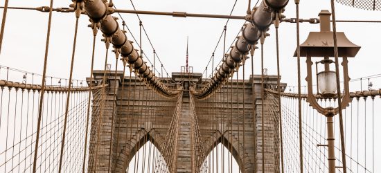 as if we are walking onto an enormous suspension bridge, there are wires on either side, arches of bricks in front