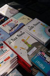 Piles of books with one in the center entitled "Le Petit Prince"