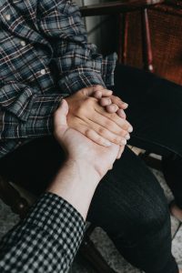 a close up of one arm outstretched so the hand can hold two hands clasped around it