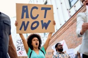 Protesters, one is holding up a sign saying ACT NOW